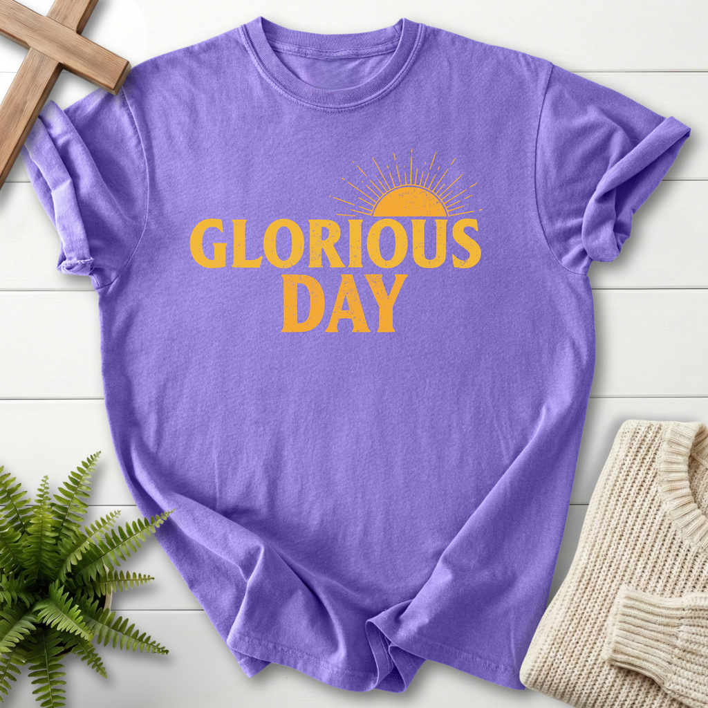 Violet women's faith t-shirt with bold golden 'Glorious Day' lettering and a retro sunrise graphic.