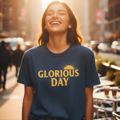 Woman smiling in the sunlight while wearing a Comfort Colors 1717 midnight “Glorious Day” t-shirt with a golden sunrise design. A joyful women’s scripture tee — uplifting faith-based apparel for women and modern Christian shirt, thoughtful Christian mom gift idea.