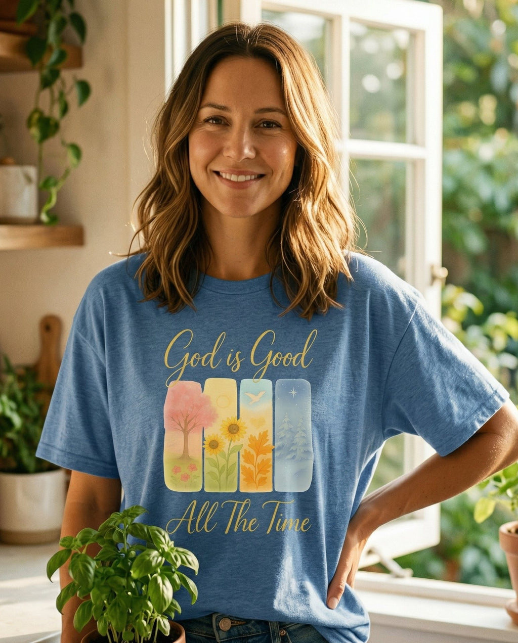 God is Good T-shirt – Blue Jean women's Christian tee, lifestyle photo in morning kitchen setting – Four watercolor seasonal panels showing a spring tree – She Wears Faith