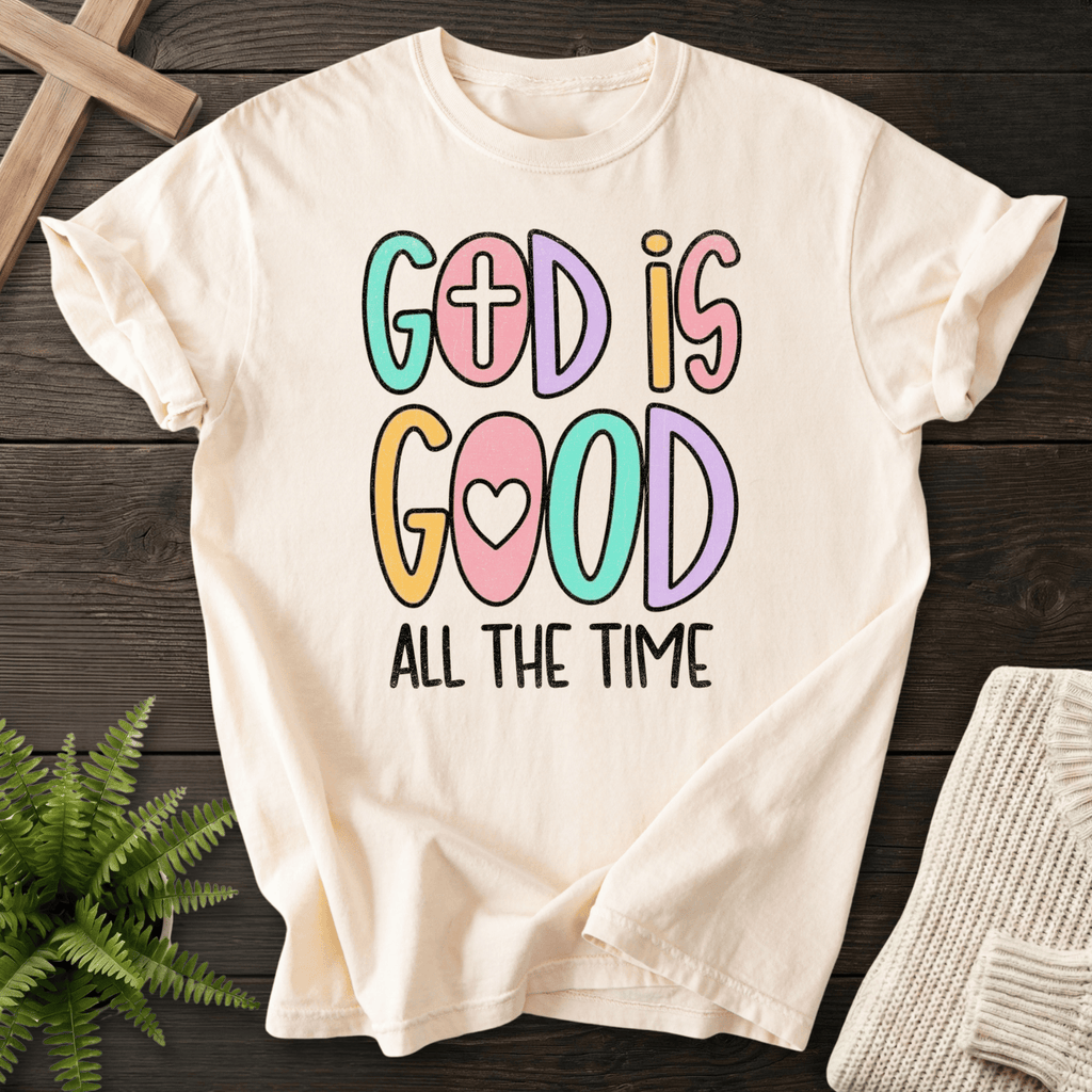 Ivory women's faith t-shirt with colorful playful 'God Is Good All The Time' bubble letters featuring a cross and heart.
