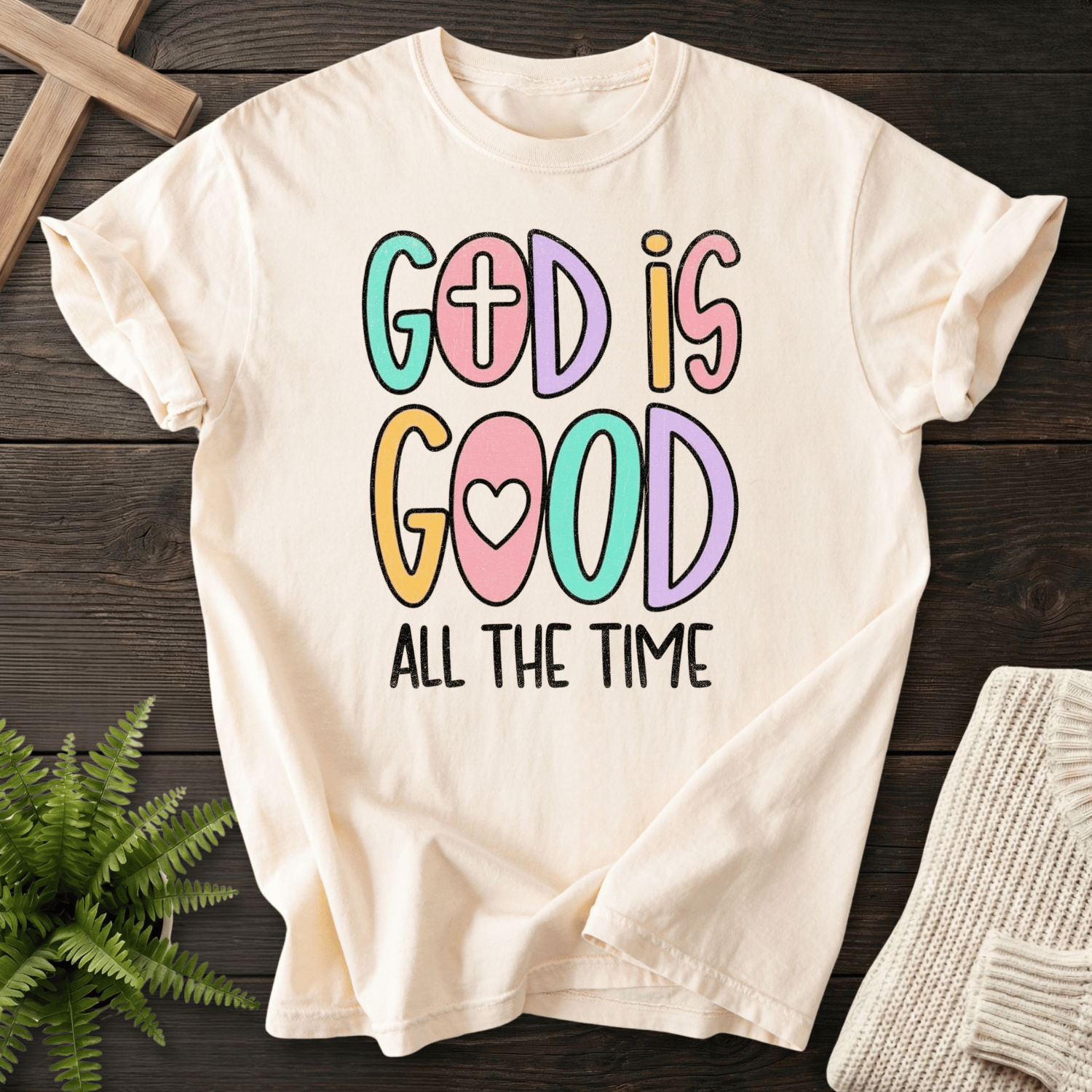 Ivory women's faith t-shirt with colorful playful 'God Is Good All The Time' bubble letters featuring a cross and heart.