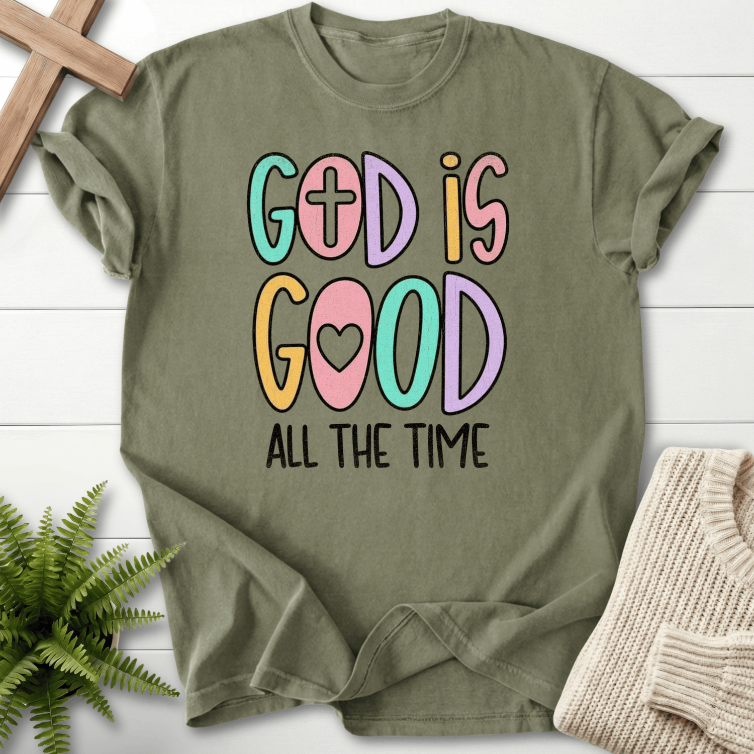 Sage women's faith t-shirt with cheerful bold 'God Is Good All The Time' in colorful outlined letters.