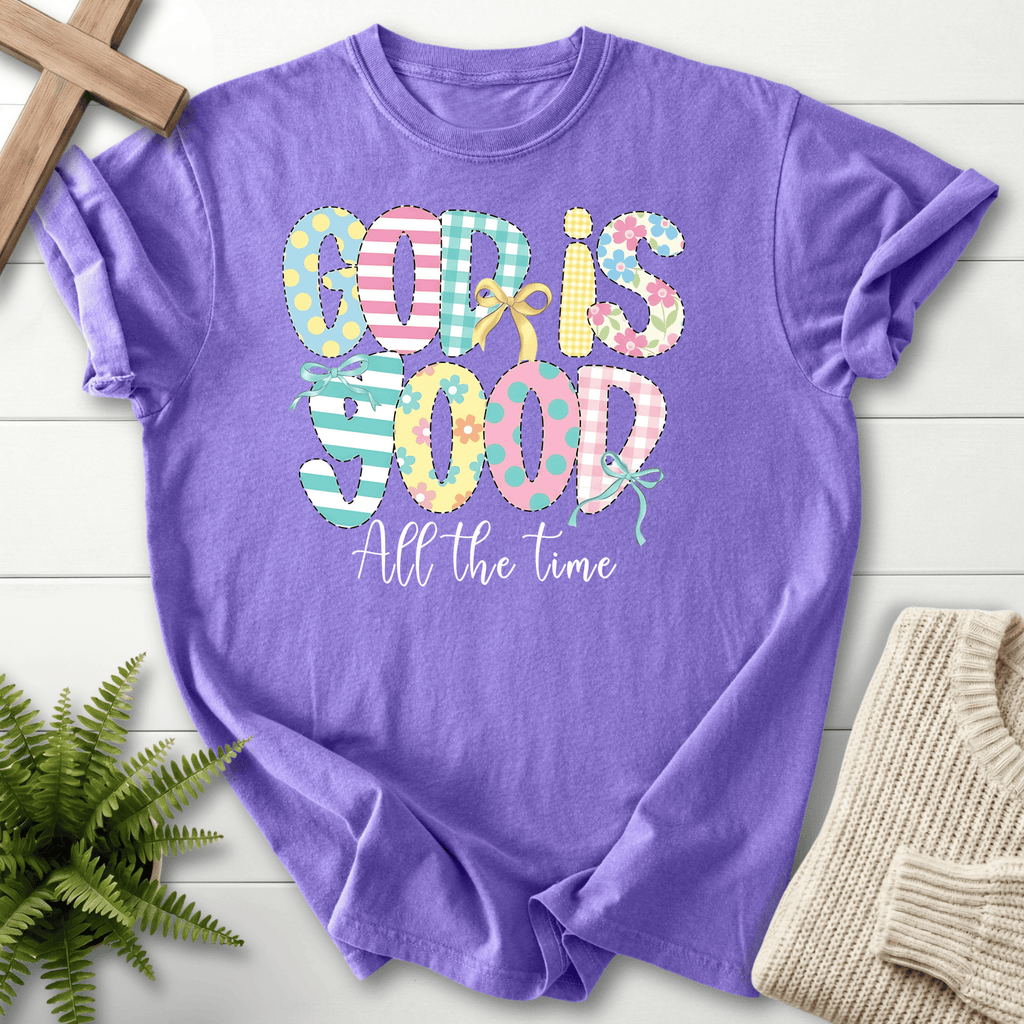 Violet women's faith t-shirt with playful patchwork 'God Is Good' lettering in pastel stripes and polka dots.