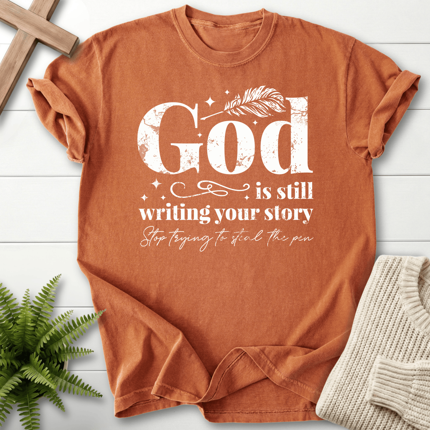 Yam women's faith t-shirt with distressed white 'God is Still Writing Your Story' script and a quill detail, Comfort Colors 1717.