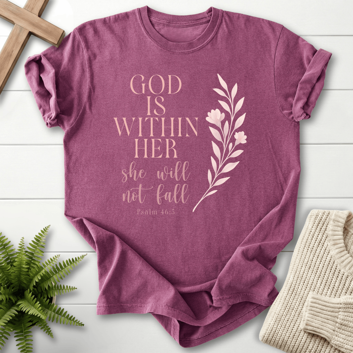 Berry Bible verse tee with 'God is Within Her, She Will Not Fall' and a tall floral stem in pink tones, inspired by Psalm 46:5.