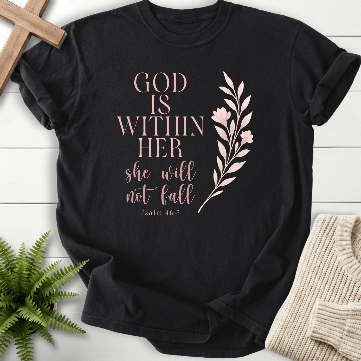 Black women's faith t-shirt with rose gold 'God is Within Her, She Will Not Fall' and a floral branch, inspired by Psalm 46:5.