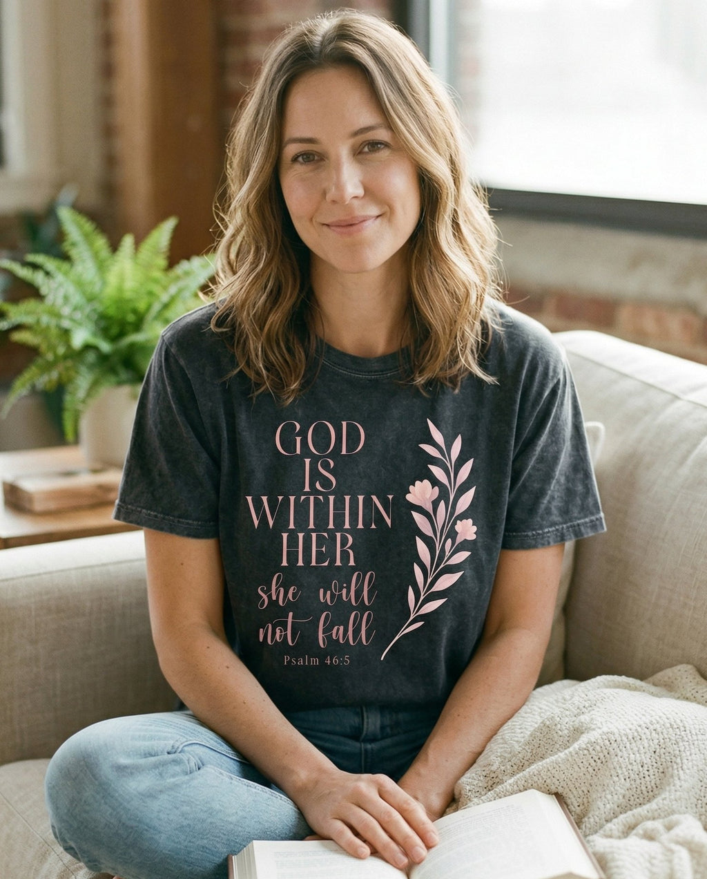 God is Within Her – Pepper women's Christian tee, lifestyle photo in cozy living room – Stacked serif and script text 'GOD IS WITHIN HER she will not fall – Psalm 46:5 – She Wears Faith