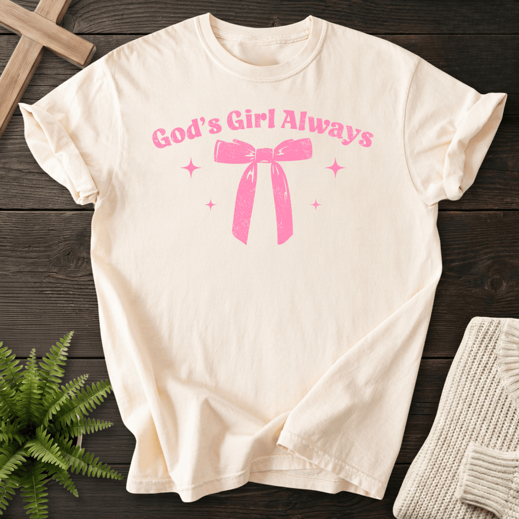 Ivory women's faith t-shirt with a coquette-style ribbon bow and 'God's Girl Always' in curved script.