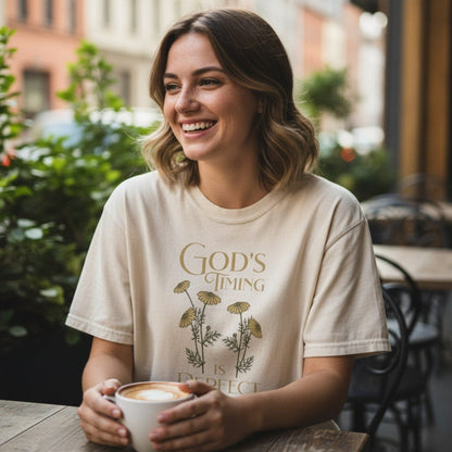 Smiling woman enjoying coffee in a Comfort Colors 1717 ivory “God’s Timing Is Perfect – Ecclesiastes 3:11” t-shirt. A serene and encouraging women’s scripture tee — soft modern Christian shirt and uplifting faith-based apparel for women, perfect Christian mom gift.