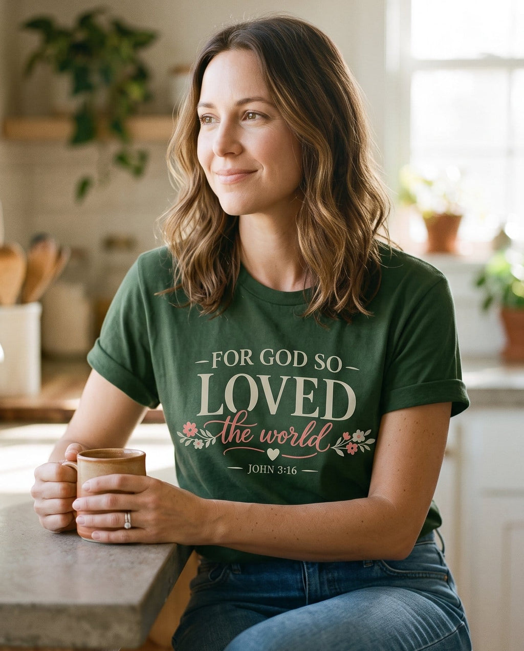 God So Love John 3:16 – Hemp women's Christian tee, lifestyle photo in morning kitchen setting – Serif and script lettering "For God So Loved the World" with pink flor – John 3:16 – She Wears Faith