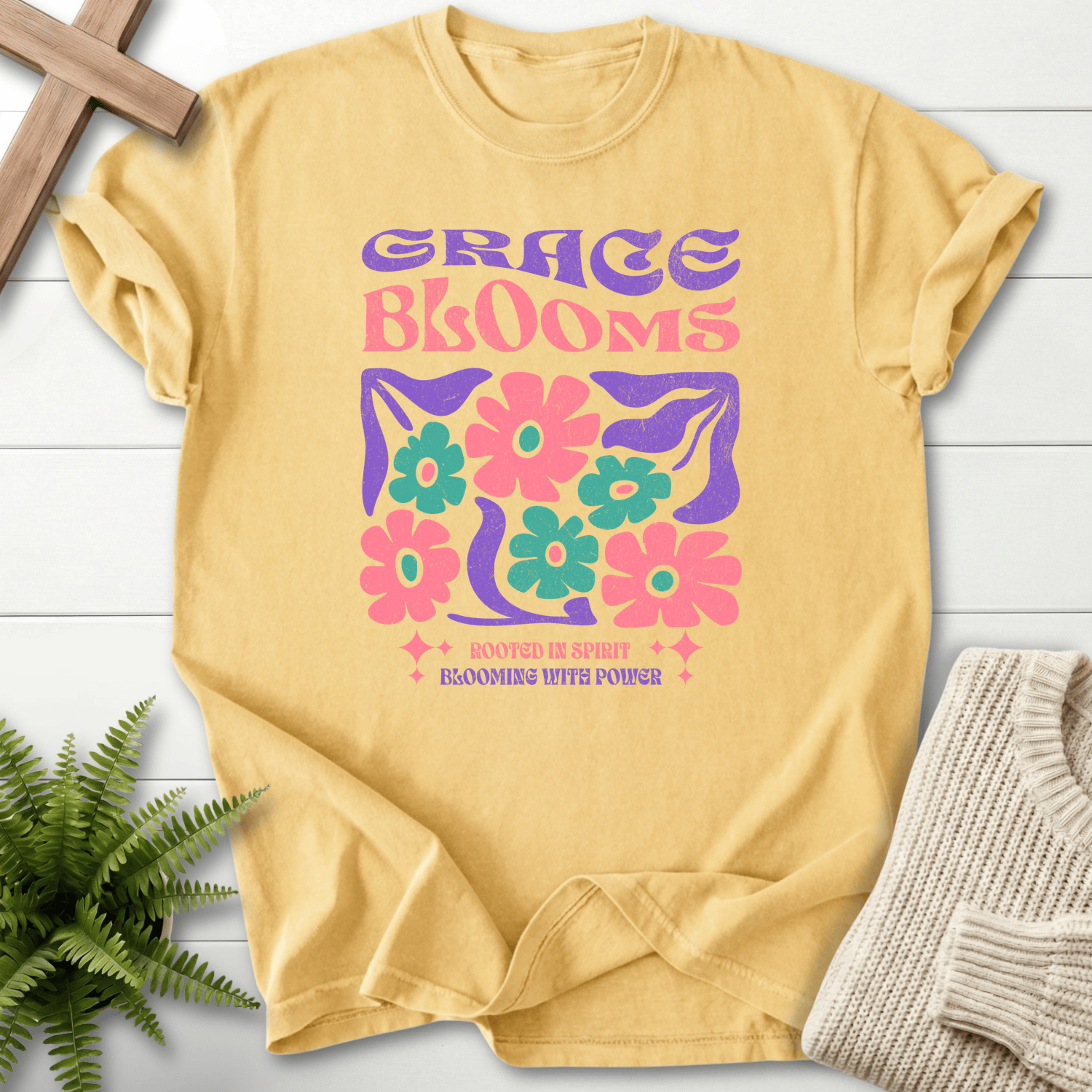 Butter women's faith t-shirt with bold purple 'Grace Blooms' in groovy retro lettering and a flower design.