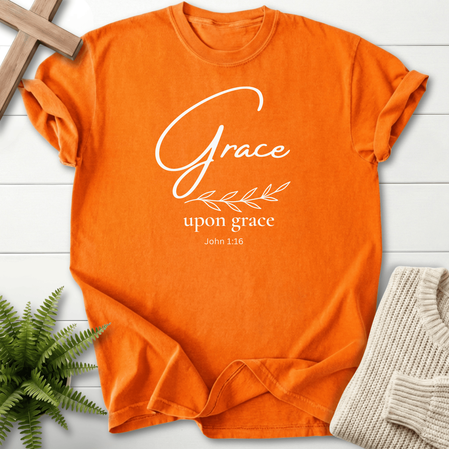 Burnt orange Bible verse tee with golden 'Grace upon grace' script and a minimalist leaf sprig, inspired by John 1:16.