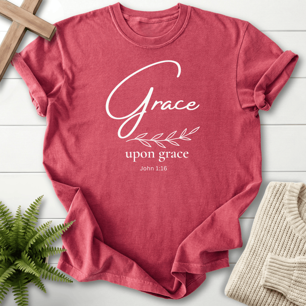 Crimson women's faith t-shirt with gold script 'Grace upon grace' and a botanical leaf accent, inspired by John 1:16.
