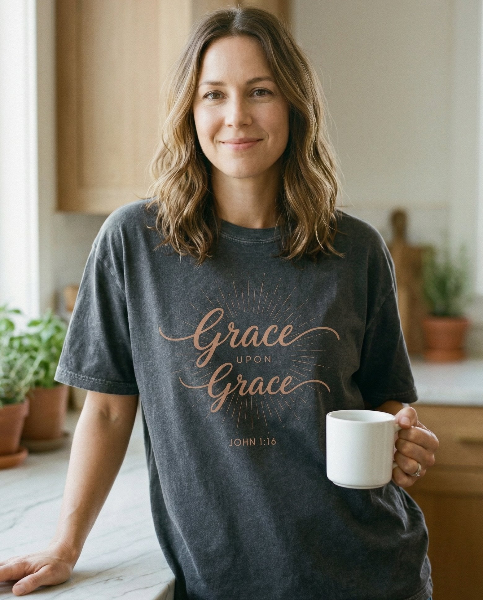Grace Upon Grace – Pepper women's Christian tee, lifestyle photo in morning kitchen setting – Elegant cursive script 'Grace upon Grace' with a starburst/sunray desi – John 1:16 – She Wears Faith