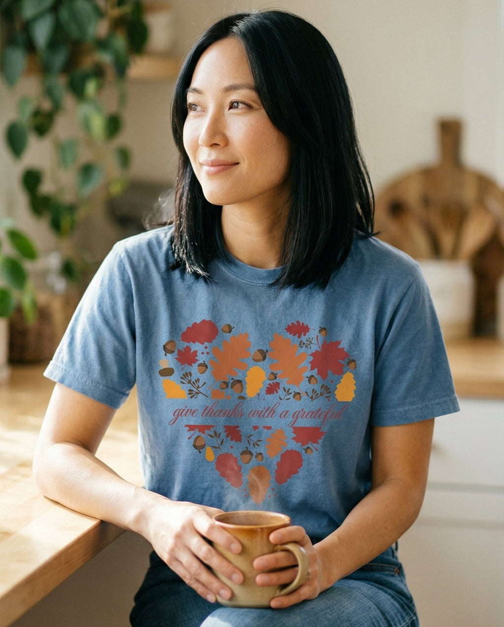 Grateful Heart Fall – Blue Jean women's Christian tee, lifestyle photo in morning kitchen setting – Heart shape filled with fall leaves – She Wears Faith