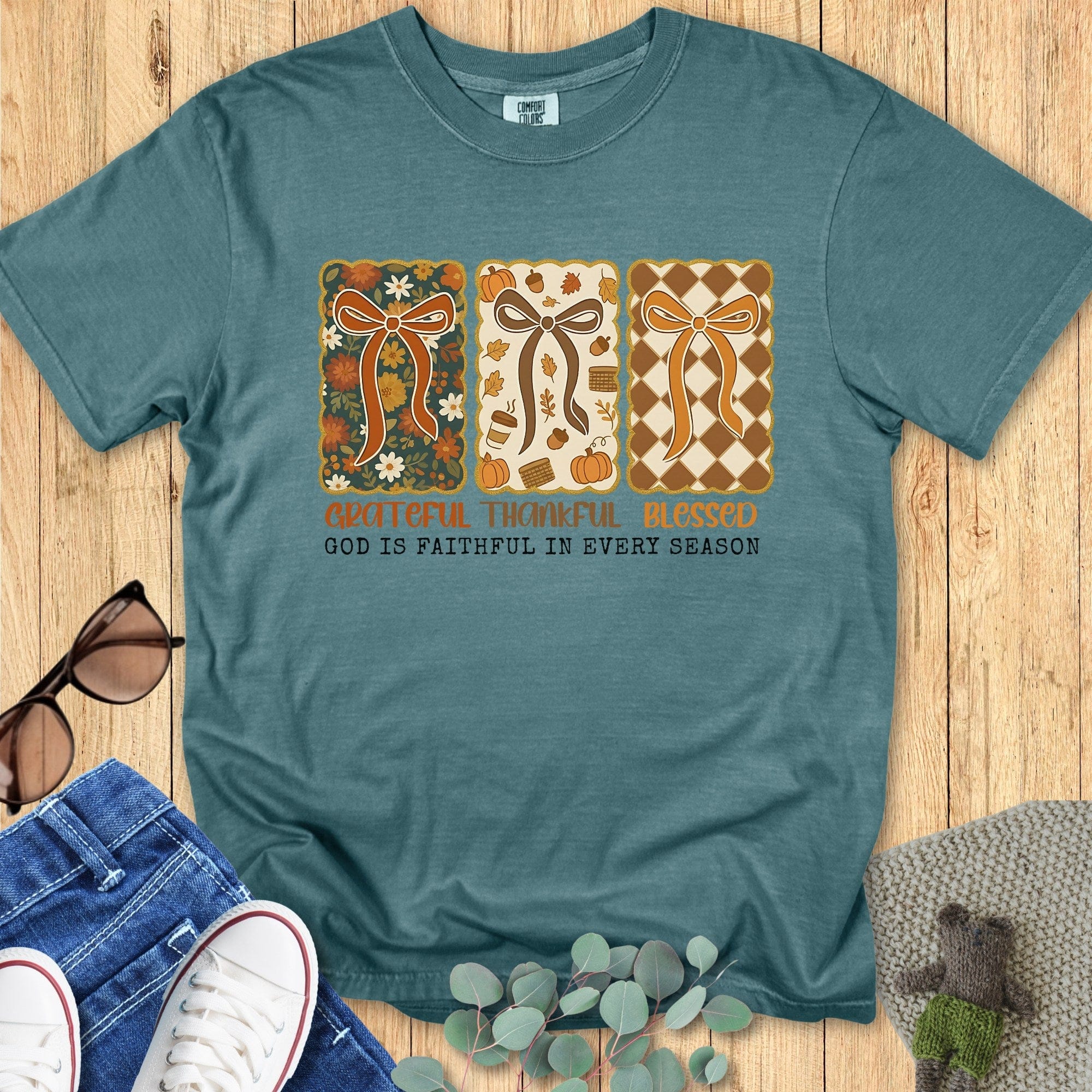 Flatlay of a Comfort Colors 1717 blue spruce “Grateful Thankful Blessed – God Is Faithful in Every Season” t-shirt with vintage patchwork bows and earthy tones. A stylish women’s scripture tee - faith-based apparel for women and modern Christian shirt, meaningful Christian mom gift idea for every season.