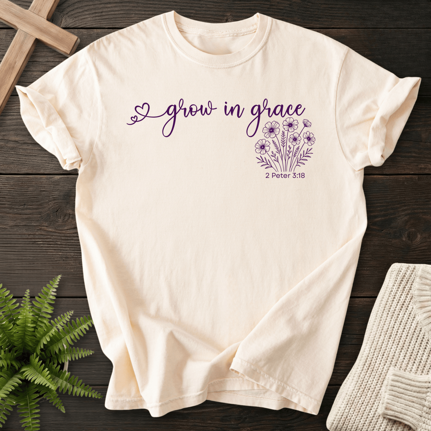 Ivory women's faith t-shirt with a heart accent, 'grow in grace' lettering, and a wildflower cluster, inspired by 2 Peter 3:18.