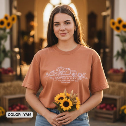 Smiling woman wearing a Comfort Colors 1717 yam “The harvest is plentiful but the laborers are few” t-shirt (Matthew 9:37) while holding sunflowers. A soft women’s scripture tee -  faith-based apparel for women and modern Christian shirt, perfect Christian mom gift idea for fall or harvest season.
