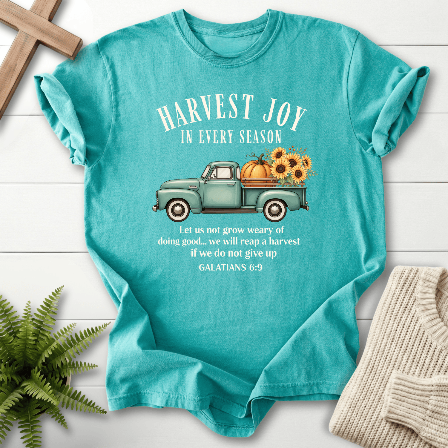 Seafoam women's faith t-shirt with a colorful pumpkin truck and 'Harvest Joy in Every Season' graphic.