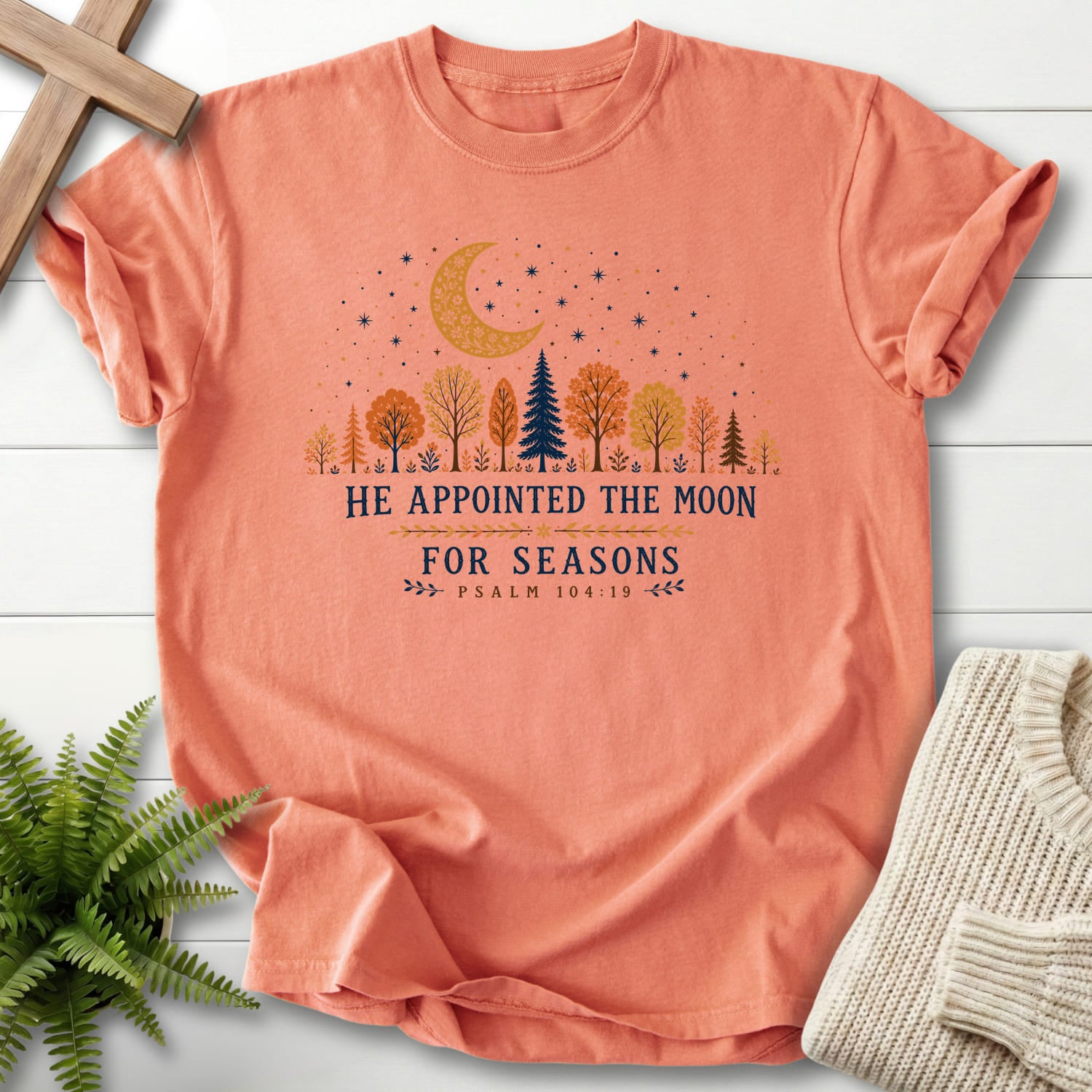 Flat lay of a Terracotta faith-inspired shirt featuring floral line art with "He Appointed the Moon for Seasons T-Shirt" Psalm 104:19.