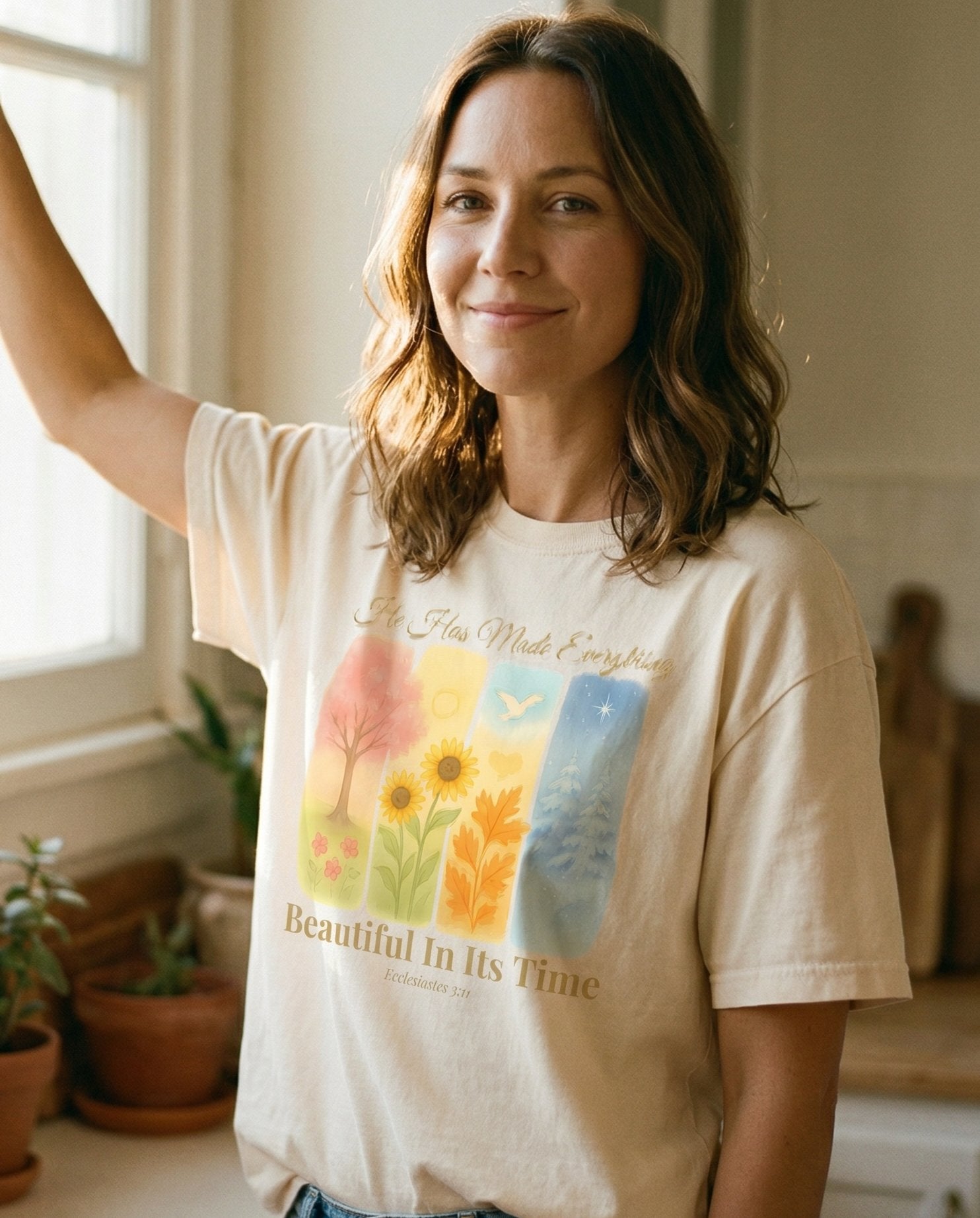 Beautiful In Its Time – Ivory women's Christian tee, lifestyle photo in morning kitchen setting – Four watercolor seasonal panels showing spring blossoms – Ecclesiastes 3:11 – She Wears Faith