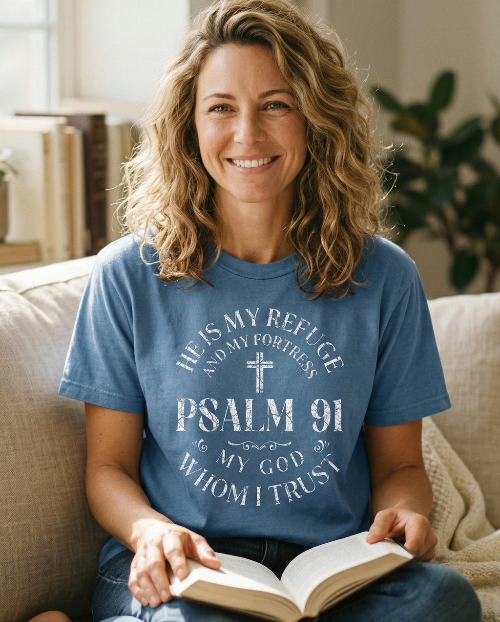 He is My Refuge – Blue Jean women's Christian tee, lifestyle photo in cozy living room – Circular badge-style distressed design with 'He is My Refuge and My Fo – Psalm 91 – She Wears Faith