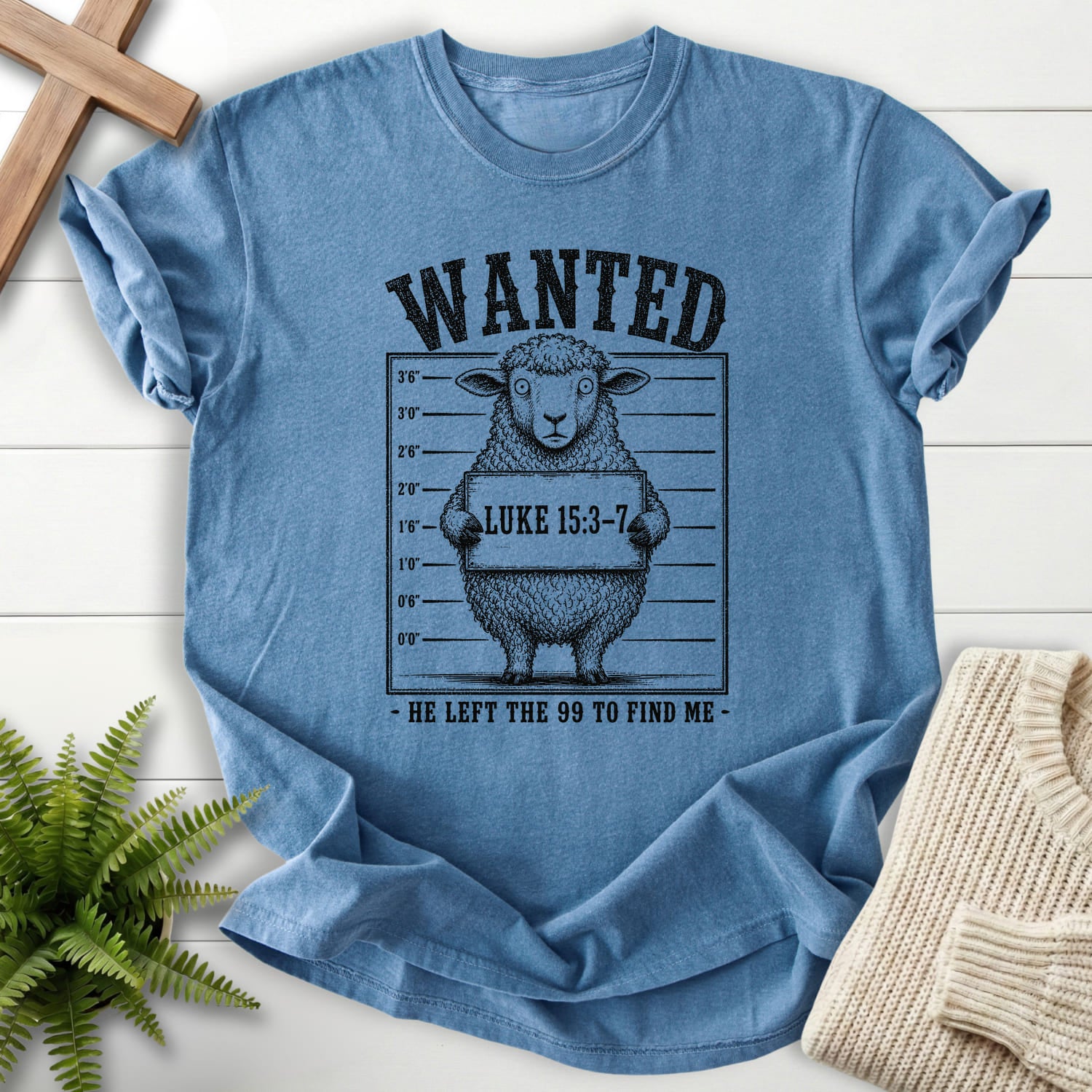Flatlay of a Blue Jean Scripture shirt with "He Left the 99 to Find me Dark T-Shirt" Luke 15:3-7.
