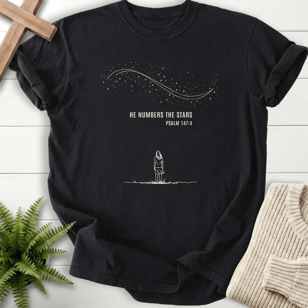 Black women's Christian t-shirt with a line-art figure under a starry sky and "He Numbers the Stars," inspired by Psalm 147:4