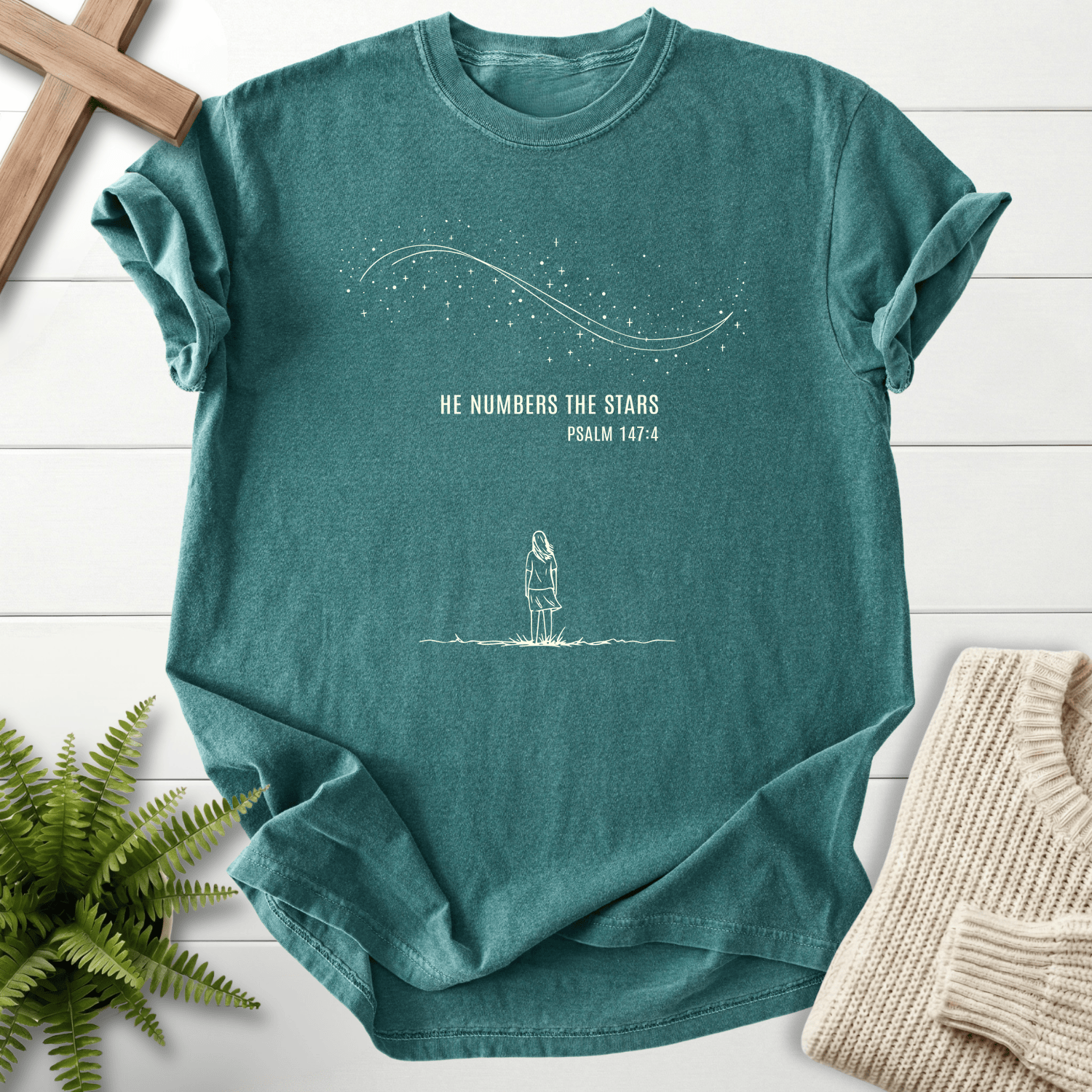 Blue Spruce women's Christian t-shirt with starfield line art, a lone figure, and "He Numbers the Stars," inspired by Psalm 147:4