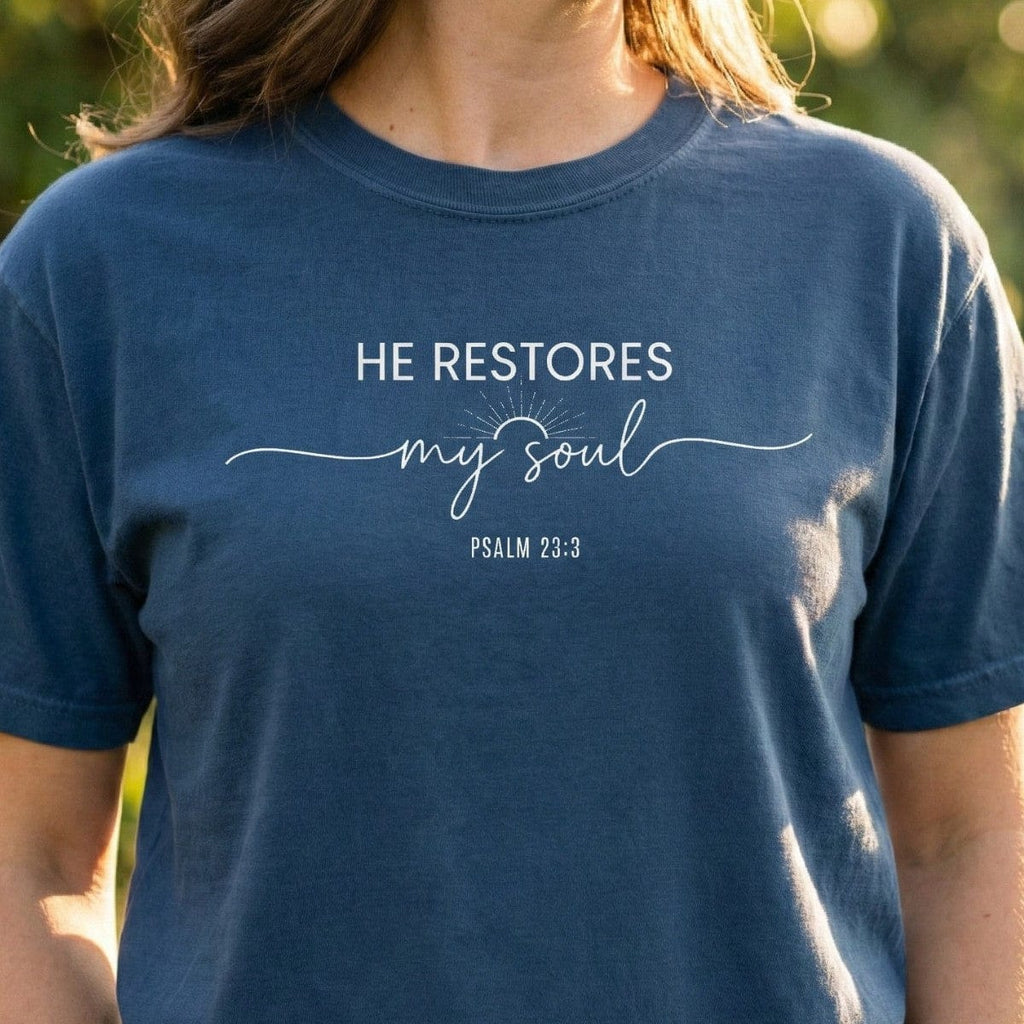 Midnight blue Christian Women's T-Shirt featuring white typography that reads "He Restores My Soul Psalm 23:3" with a sunrise graphic.