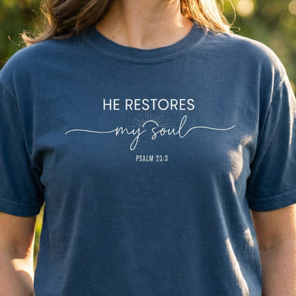 Midnight blue Christian Women's T-Shirt featuring white typography that reads "He Restores My Soul Psalm 23:3" with a sunrise graphic.