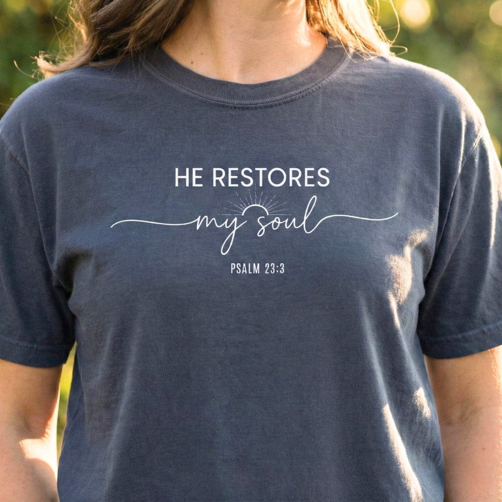 Pepper dark grey Bible Verse Shirt displaying the text "He Restores My Soul" and "Psalm 23:3" in a mix of sans-serif and script fonts.