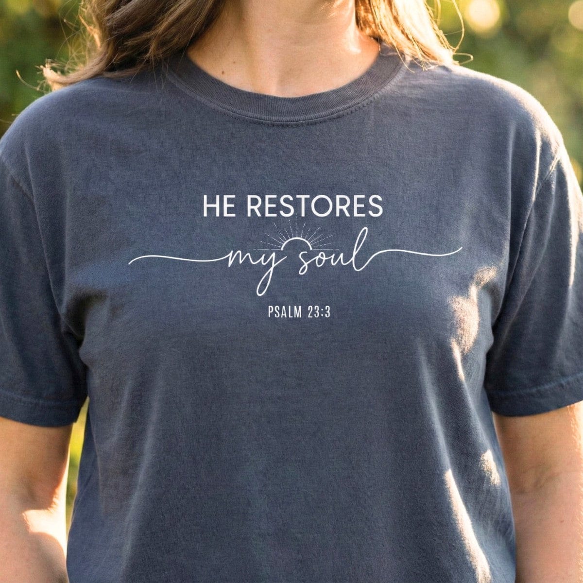 Pepper dark grey Bible Verse Shirt displaying the text "He Restores My Soul" and "Psalm 23:3" in a mix of sans-serif and script fonts.
