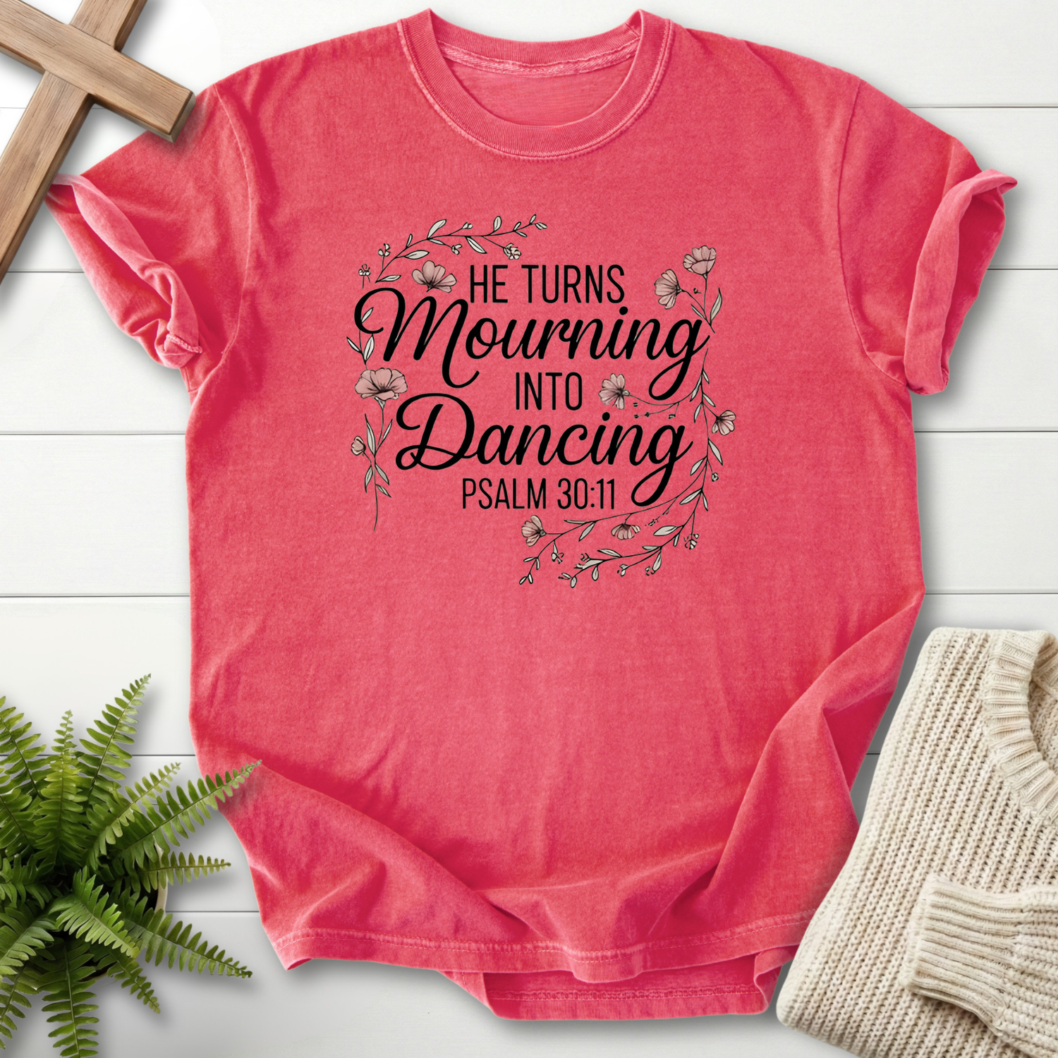 Watermelon women's Christian t-shirt with bold mixed-type "He Turns Mourning Into Dancing" lettering inside a floral wreath