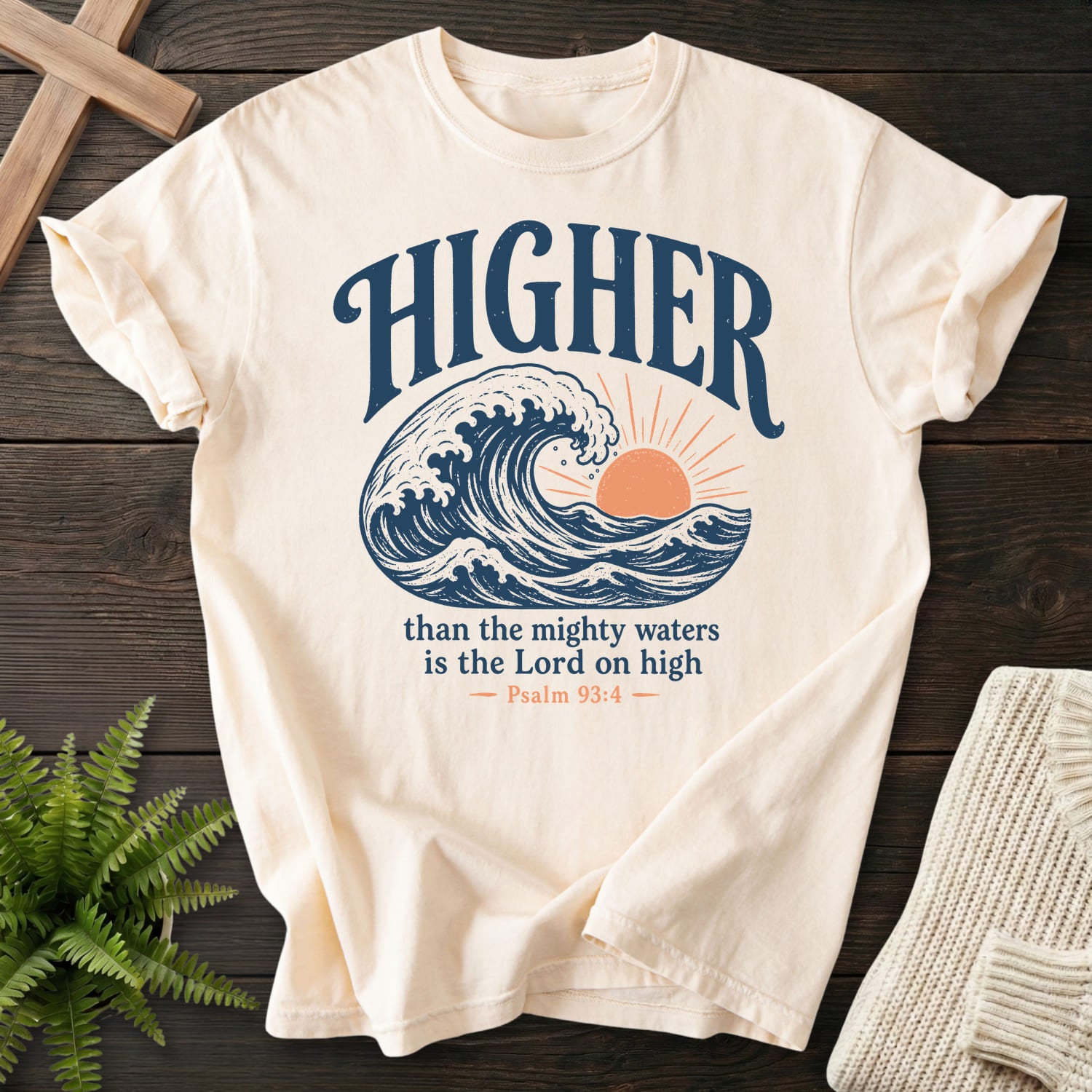 Flat lay of an Ivory Comfort Colors 1717 Christian t-shirt for women featuring sunrise graphic with "Higher Than the Mighty Waters T-Shirt".