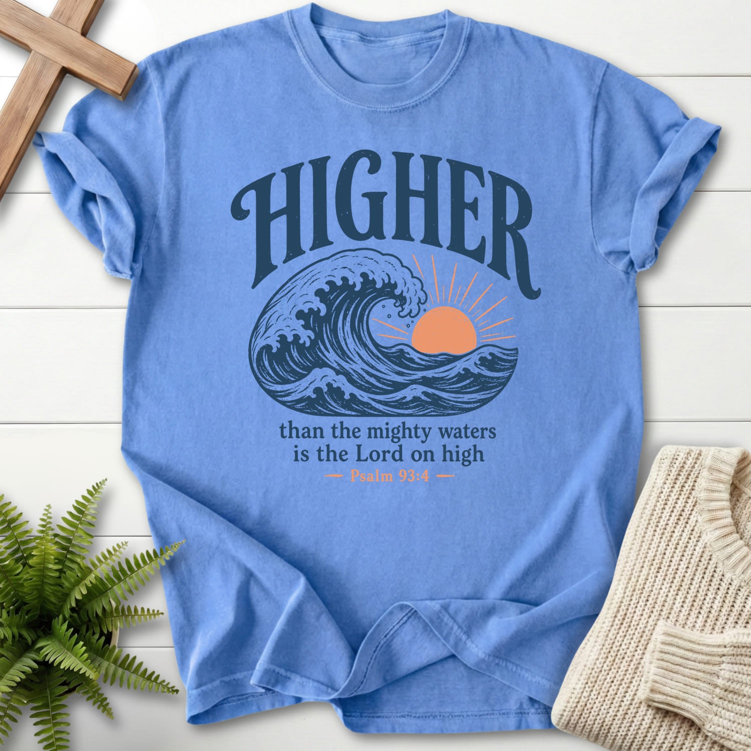Flatlay of a Mystic Blue faith-based tee with sunrise graphic with "Higher Than the Mighty Waters T-Shirt".