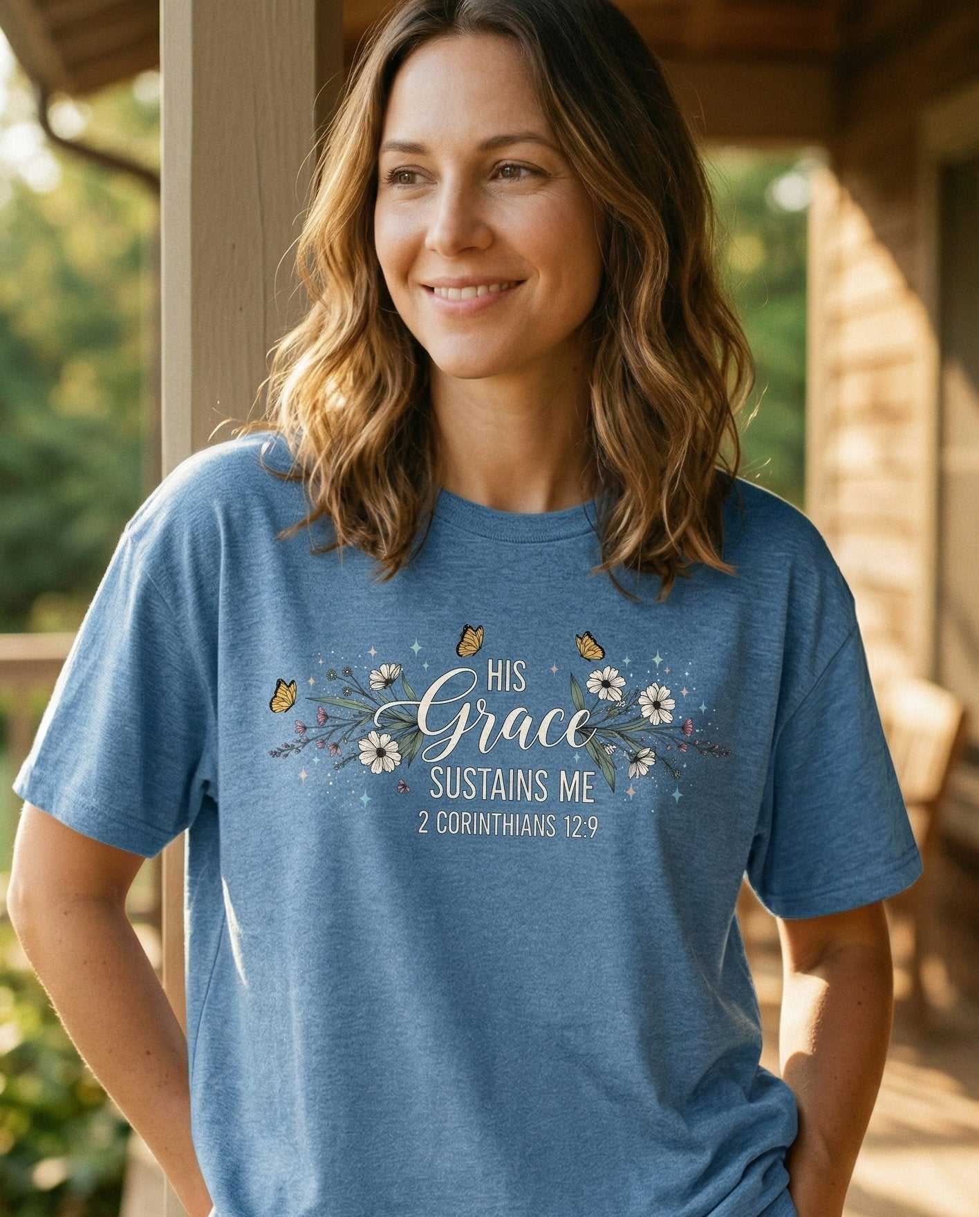 Grace Sustains Me – Blue Jean women's Christian tee, lifestyle photo in sunny porch – Floral garland with small butterflies framing 'His Grace Sustains Me'  – 2 Corinthians 12:9 – She Wears Faith