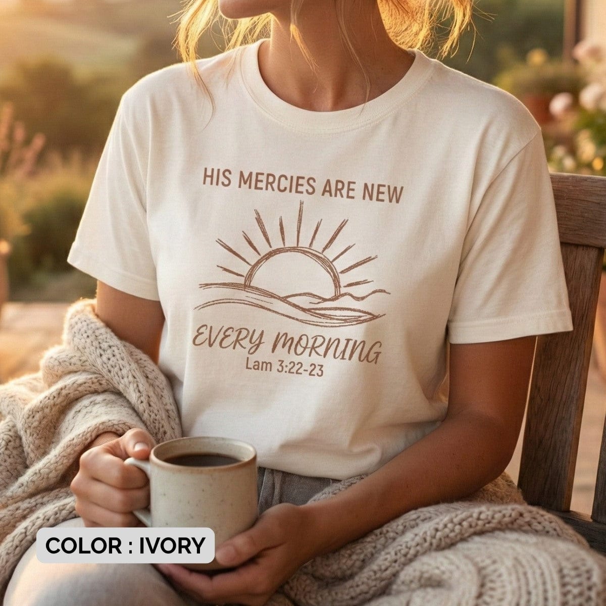 oman holding a coffee mug while wearing an Ivory Comfort Colors 1717 tshirt with brown typography. Lifestyle photography of a Christian women tee featuring "His Mercies Are New," showcasing cozy US faith wear.