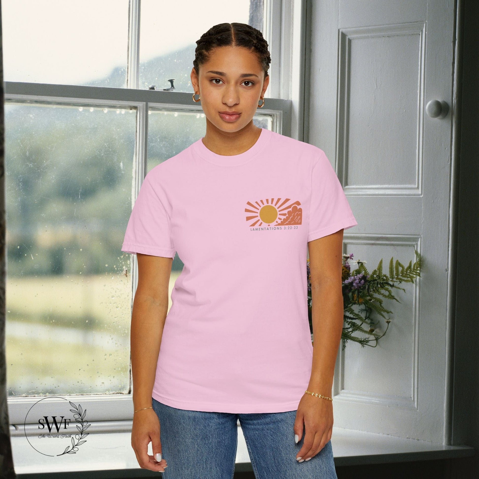 Person wearing a pink t-shirt with a sun graphic design indoors.