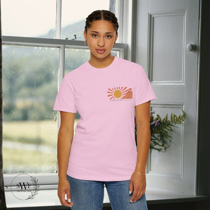 Person wearing a pink t-shirt with a sun graphic design indoors.