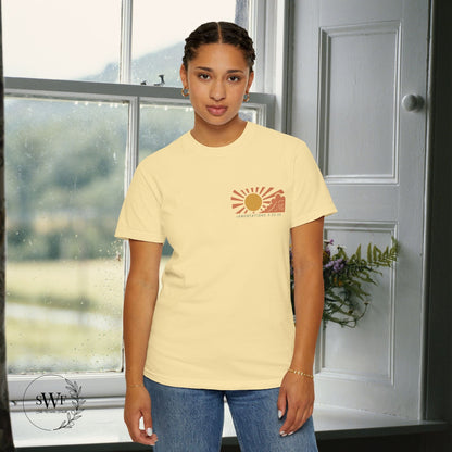 Person wearing a beige t-shirt with a sun graphic design indoors.