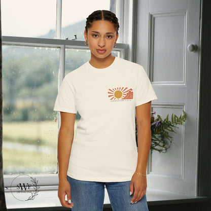Person wearing a white t-shirt with a logo in a room with a window and door.