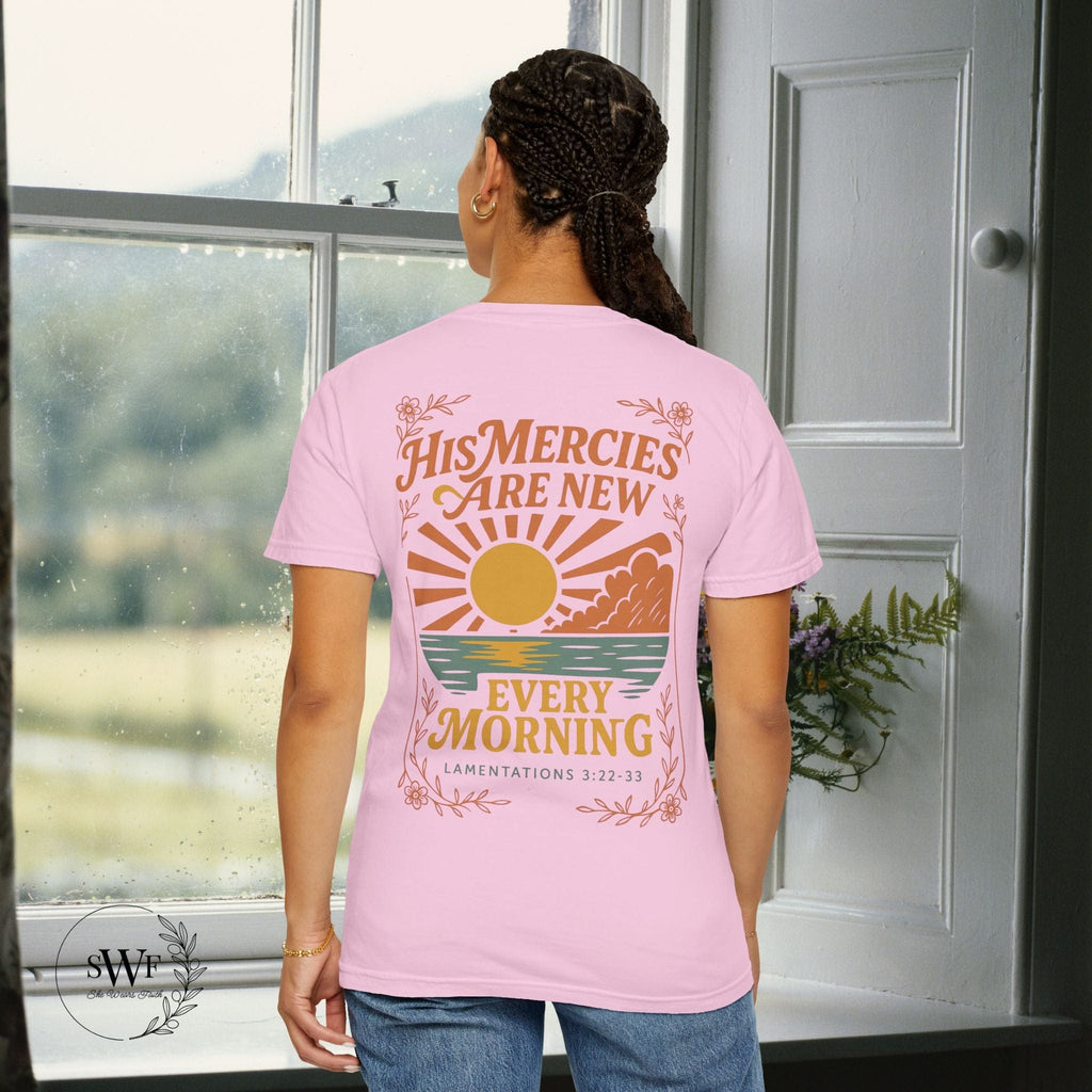 Back view of a light pink blossom Christian t-shirt with floral accents and a sunrise graphic reading “His Mercies Are New Every Morning – Lamentations 3:22–33.”