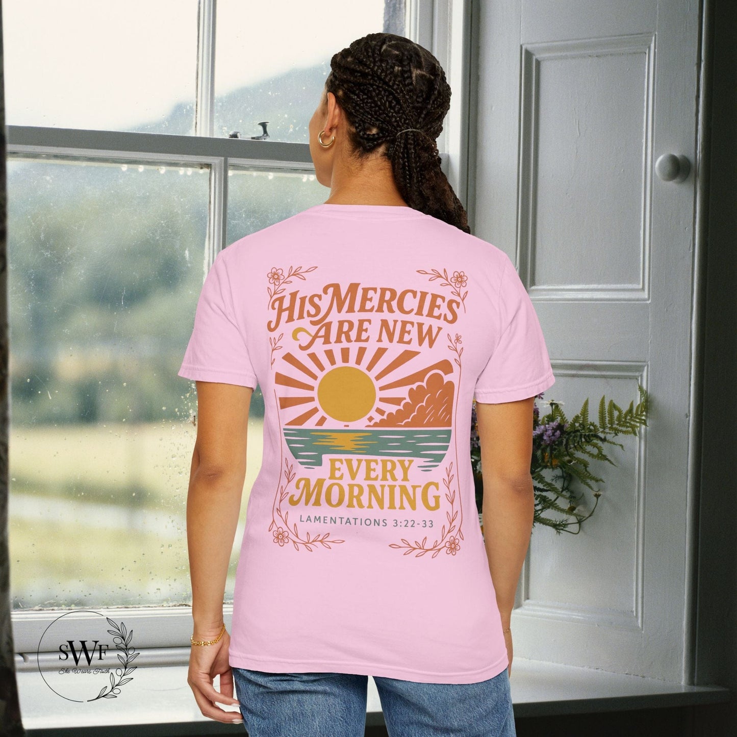 Back view of a light pink blossom Christian t-shirt with floral accents and a sunrise graphic reading “His Mercies Are New Every Morning – Lamentations 3:22–33.”