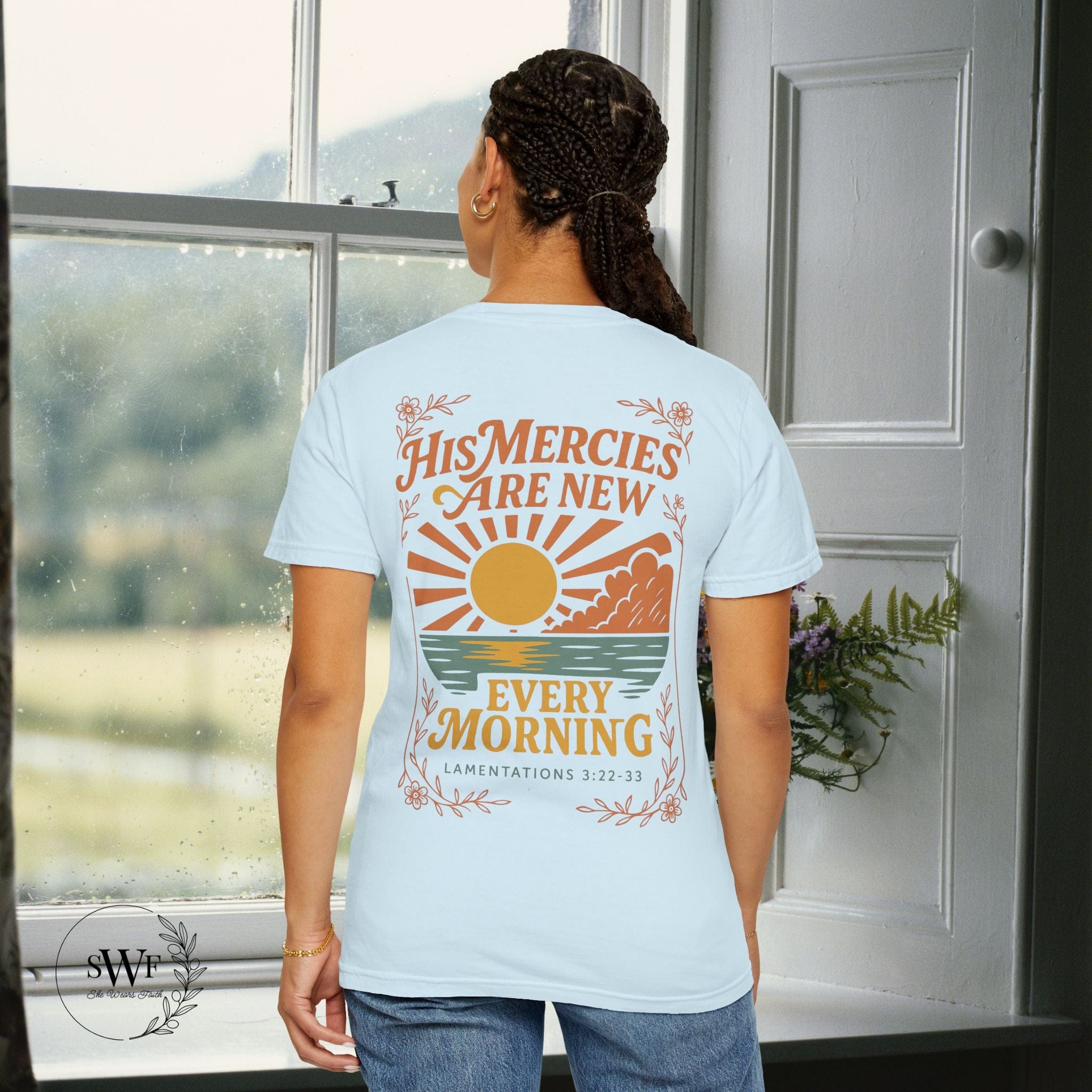 Back view of a soft blue chambray Christian t-shirt featuring a sunrise graphic and “His Mercies Are New Every Morning – Lamentations 3:22–33.”