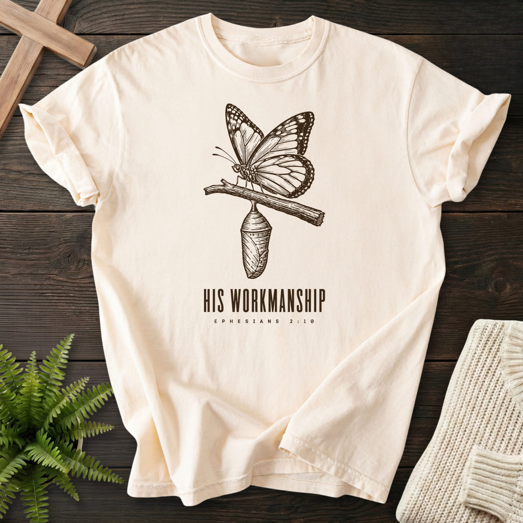 Flatlay of an Ivory faith-inspired shirt with butterfly artwork with "His Workmanship T-Shirt".