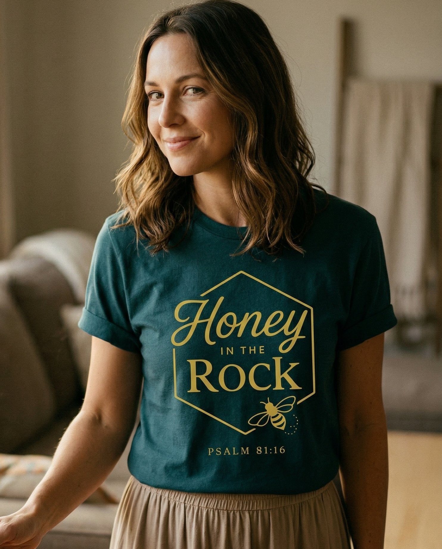 Honey in the Rock – Blue Spruce women's Christian tee, lifestyle photo in cozy living room – Hexagonal honeycomb frame in gold containing 'Honey in the Rock' in sc – Psalm 81:16 – She Wears Faith