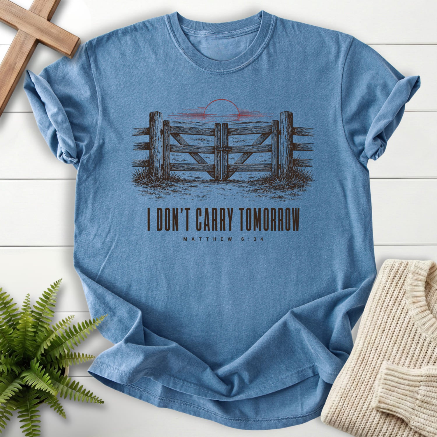 Flatlay of a Blue Jean faith-inspired shirt with "I Don't Carry Tomorrow T-Shirt" Matthew 6:34.