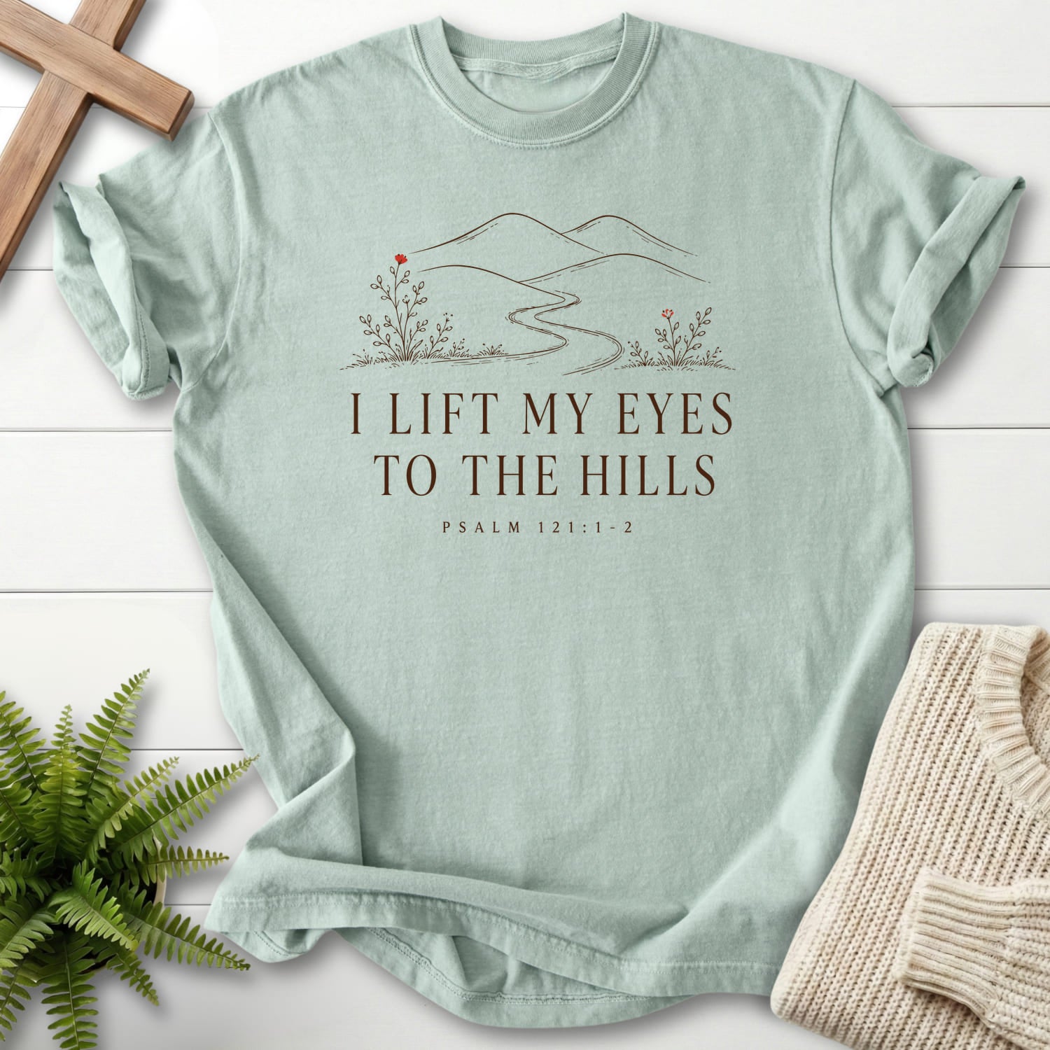 Flat lay of a Bay Christian graphic tee featuring floral line art with "I Lift My Eyes to the Hills T-Shirt" Psalm 121:1-2.