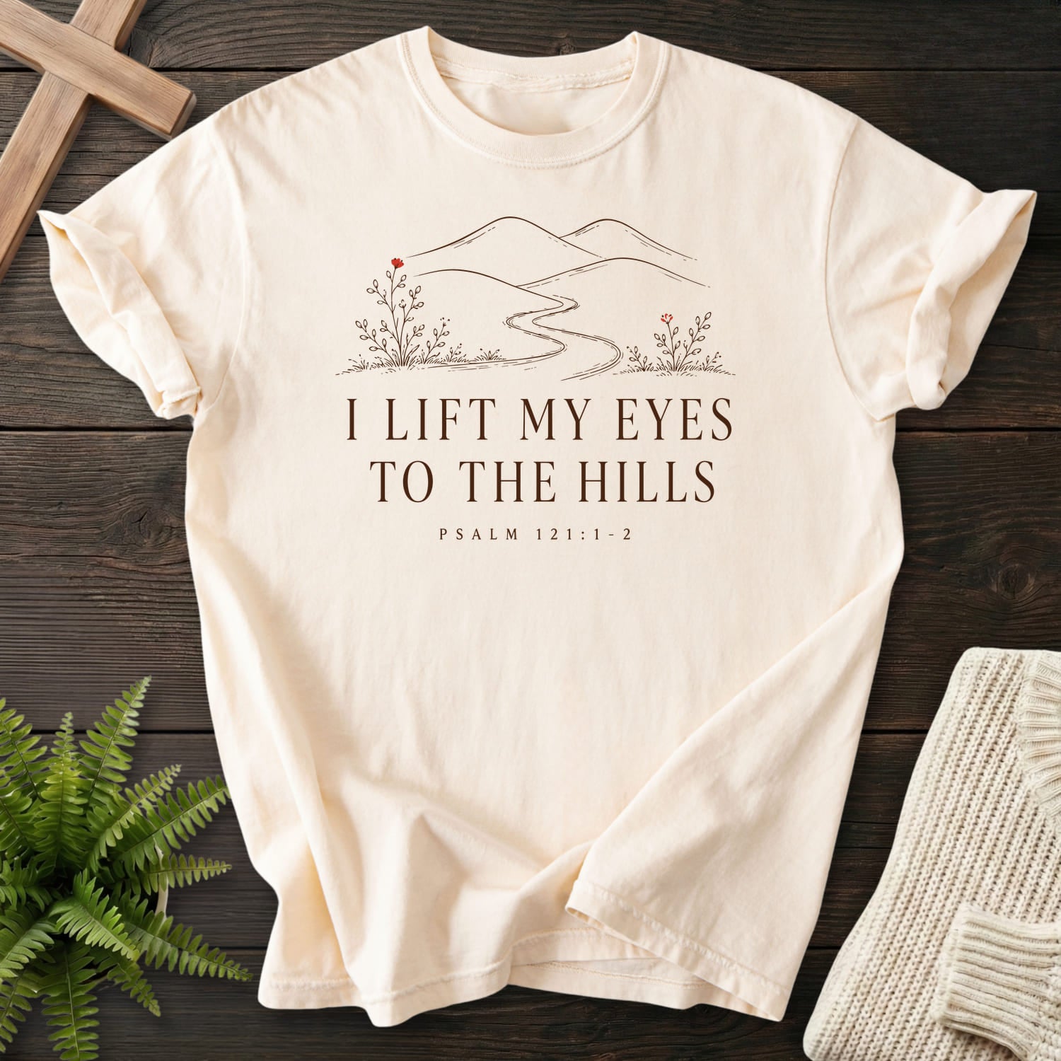 Flatlay of an Ivory Christian t-shirt for women with floral line art with "I Lift My Eyes to the Hills T-Shirt" Psalm 121:1-2.